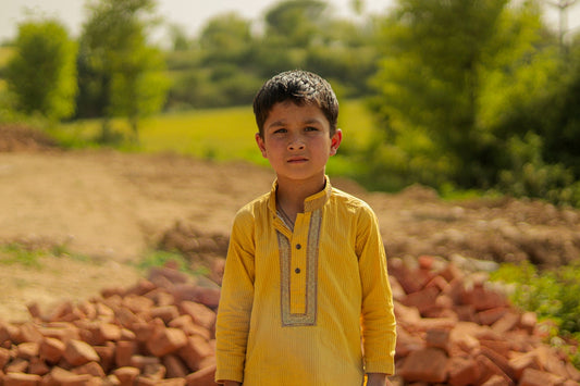 a young boy standing in front of a pile of rocks
