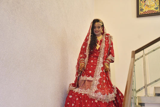 A bride in a red dress posing on stairs.